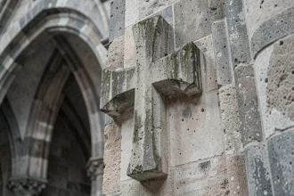 Croix de Lorraine sculptée en pierre ancienne sur un mur de cathédrale médiévale gothique