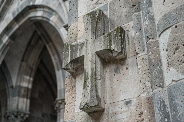 Croix de Lorraine sculptée en pierre ancienne sur un mur de cathédrale médiévale gothique