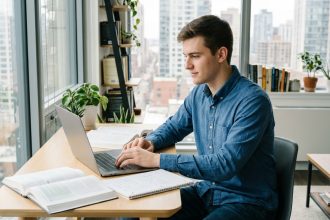 Jeune homme concentré travaillant sur son laptop dans un appartement moderne