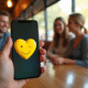 Smartphone affichant un cœur jaune dans un café lumineux